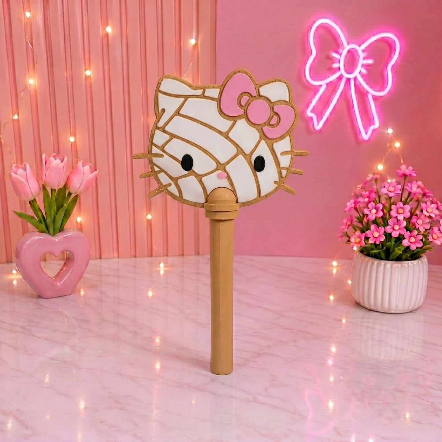 Hello Kitty-themed selfie stick with pink flowers and neon bow in the background