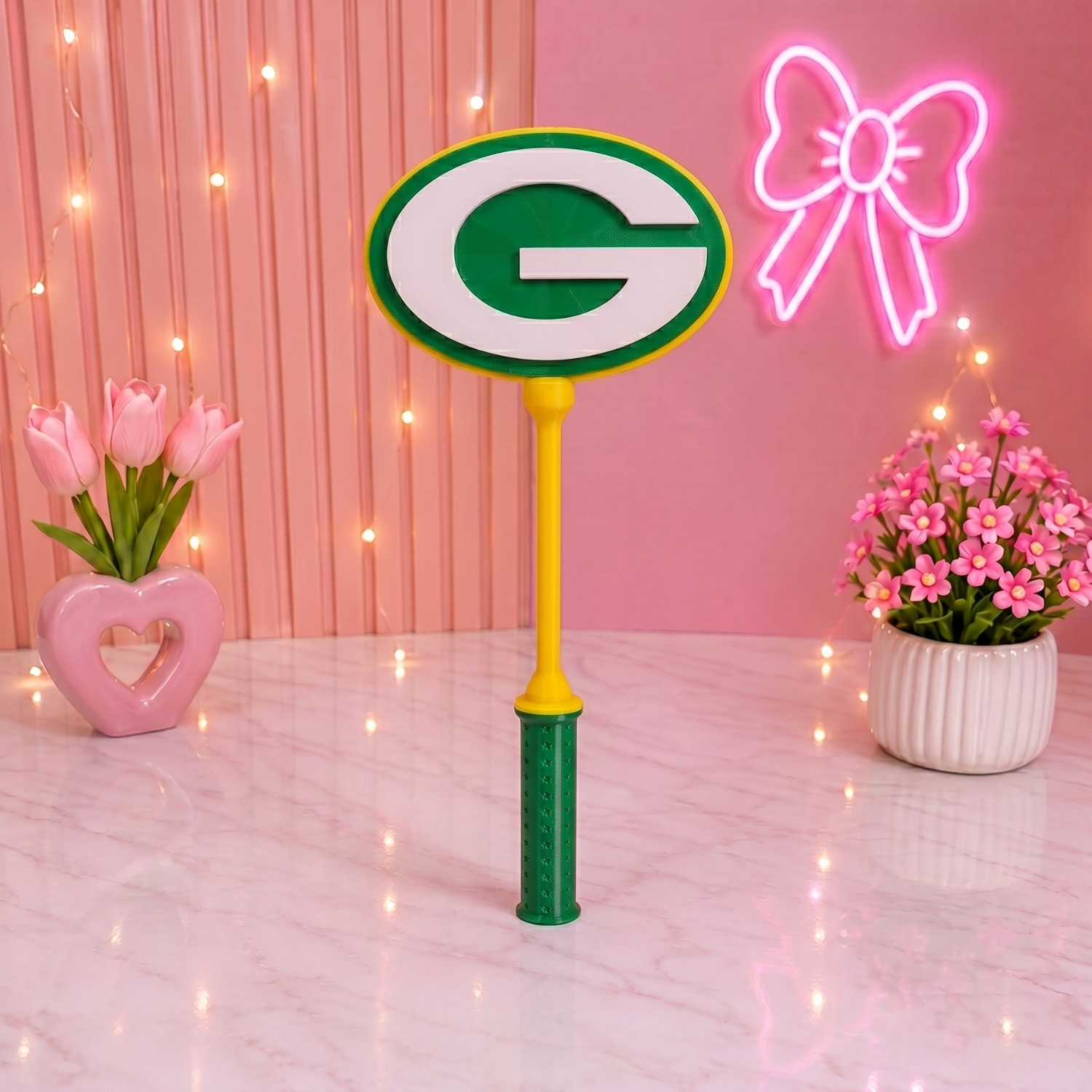 Decorative paddle with a green 'G' logo on a pink background with flowers and lights.